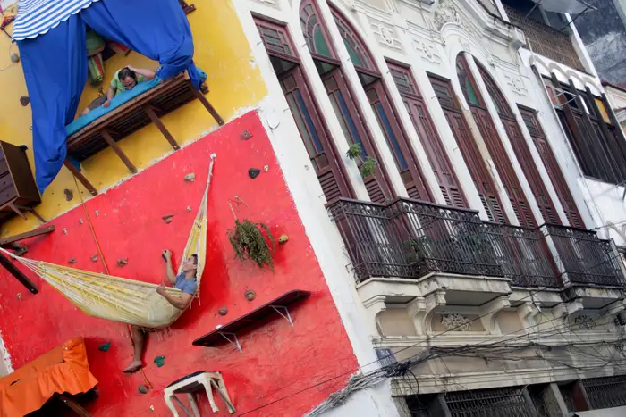 brazilian-artists-tiago-primo-top-and-his-brother-gabriel-built-a-vertical-house-on-a-climbing-wall-in-rio-de-janeiro-they-had-shelves-counters-a-hammock-and-a-bed-but-used-the-bathroom-inside-the-art-gallery-next-doo